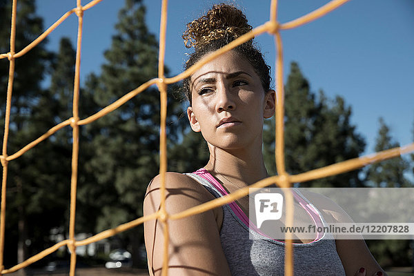 Porträt einer Frau hinter einem Fussballtornetz  die wegschaut