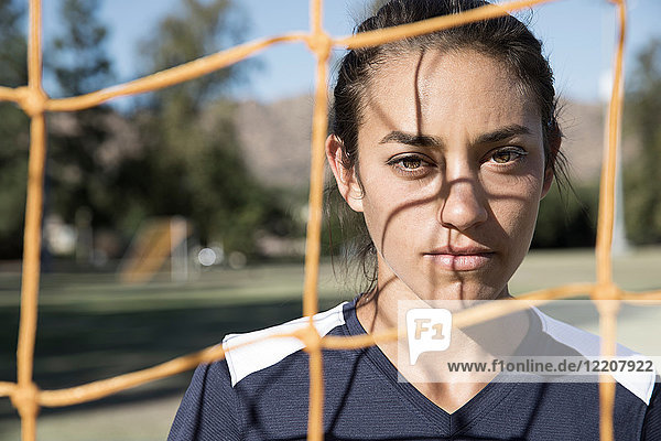 Porträt einer Frau hinter einem Fußballtornetz  die in die Kamera schaut