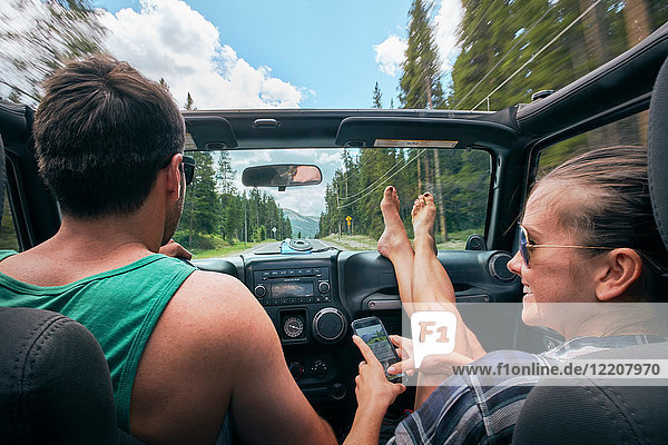 Junge Frau mit Smartphone fährt auf Road Trip mit ihrem Freund  Breckenridge  Colorado  USA