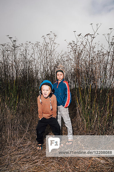 Portrait of two brothers outdoors in rural setting wearing knitted hats
