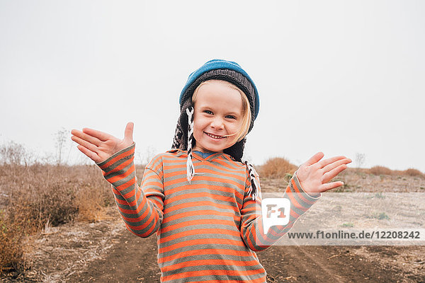 Portrait of boy on in rural setting gesturing with hands