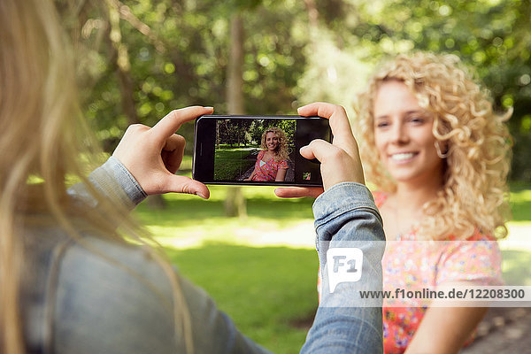 Woman taking photograph of friend using smartphone