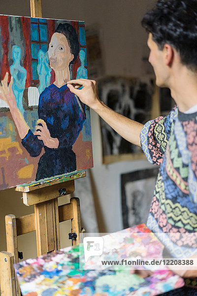 Männlicher Künstler malt Leinwand auf Staffelei im Künstleratelier