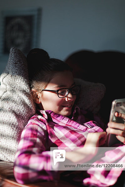 Girl relaxing on sofa  looking at smartphone