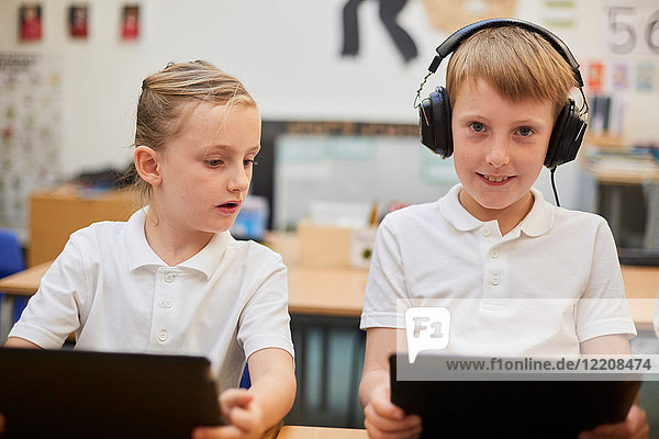Schoolboy listening to headphones in class at primary school  portrait