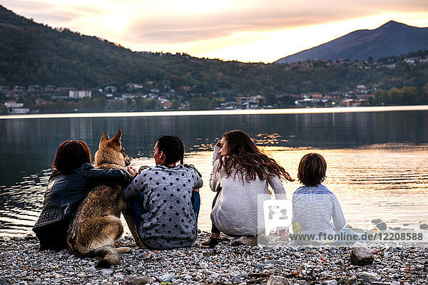 Rückansicht eines Jungen mit Familie und Hund am Fluss in der Abenddämmerung  Vercurago  Lombardei  Italien