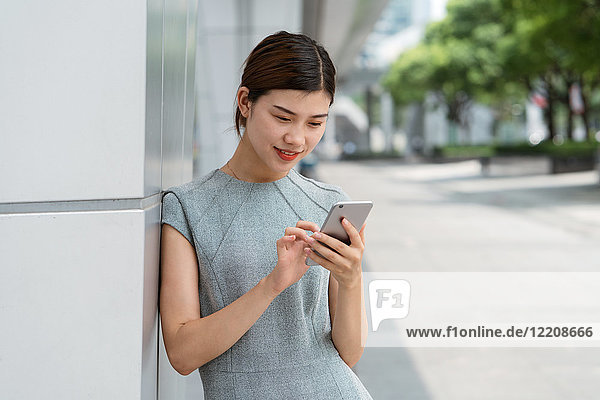 Junge Geschäftsfrau nutzt Touchscreen von Smartphones in der Stadt  Shanghai  China