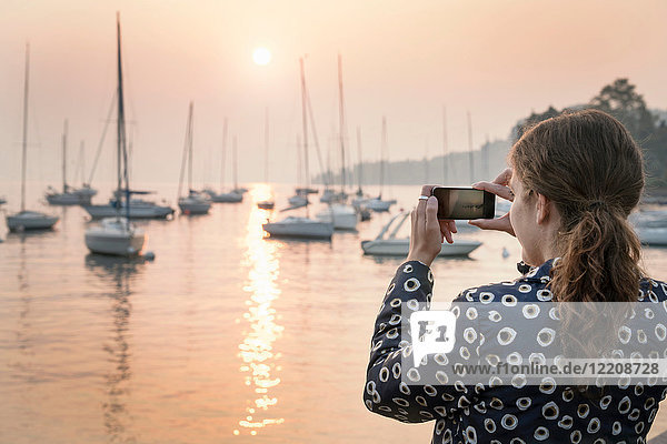 Rückansicht einer Frau  die Boote bei Sonnenuntergang fotografiert  Lazise  Venetien  Italien  Europa