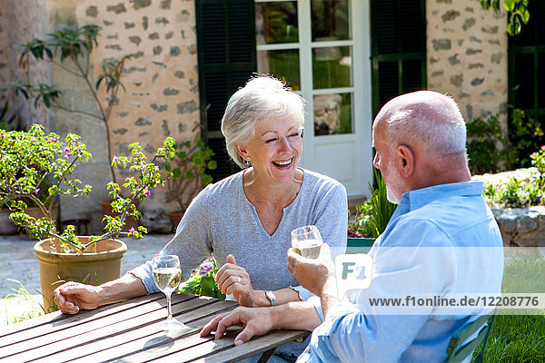 Senior couple sitting in garden  enjoying glass of wine