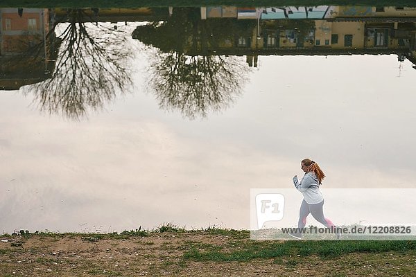 Kurvenreiche junge Läuferin läuft am Flussufer