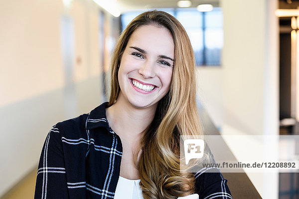 Porträt einer jungen glücklichen Geschäftsfrau im Bürokorridor  Kopf und Schultern