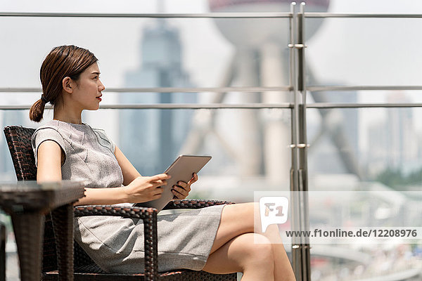 Junge Geschäftsfrau mit digitalem Tablet im Bürgersteig-Café im Finanzzentrum von Shanghai  Shanghai  China