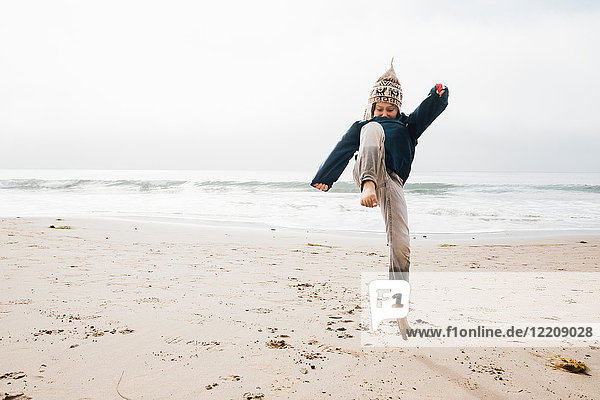 Young boy on beach jumping mid air