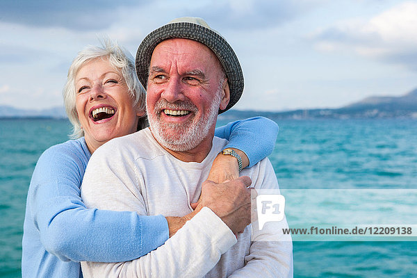 Couple hugging and laughing by seaside