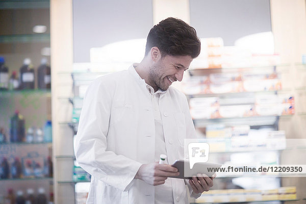 Young male pharmacist using digital tablet in pharmacy