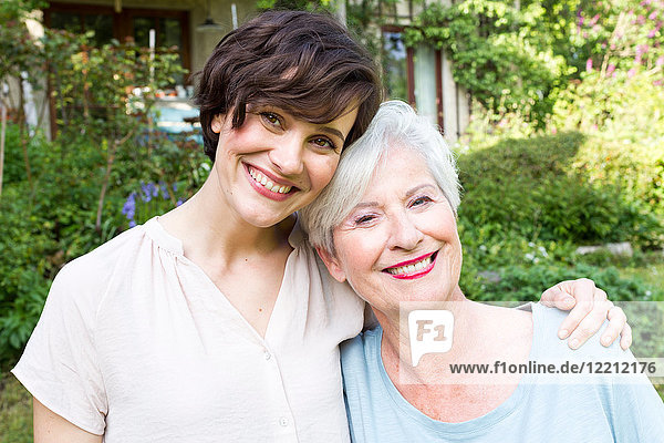 Porträt einer älteren Frau mit erwachsener Tochter  im Freien  lächelnd