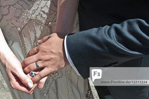 Bride and groom  holding hands  close-up  mid section