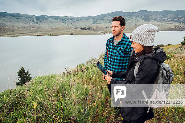 Couple hiking  standing beside Dillon Reservoir  young woman holding digital tablet  Silverthorne  Colorado  USA