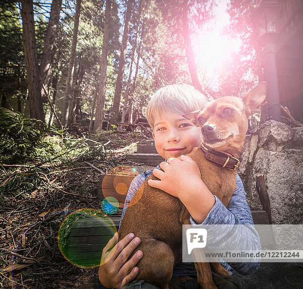 Junge trägt Hund im Wald