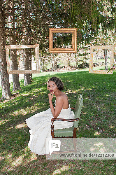 Portrait of bride wearing wedding dress  sitting in chair  outdoors