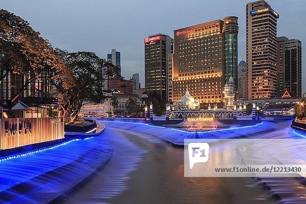 Office Buildings And Sultan Abdul Samad Jamek Mosque With Water Fountain Lit At Night On The Banks Of The Klang And Gombak Rivers