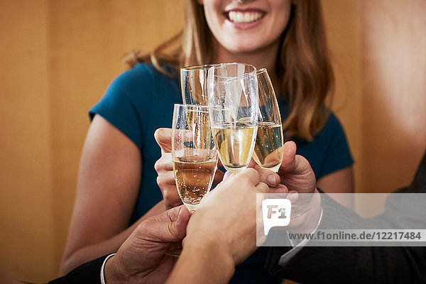 Geschäftsteam stößt bei Bürofeier mit Champagner an  angeschnitten