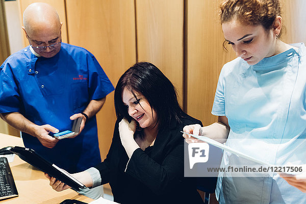 Zahnarzt und Zahnarzthelferin mit Patient  Blick auf das digitale Tablett