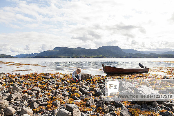 Boy playing amongst rocks by fjord  Aure  More og Romsdal  Norway