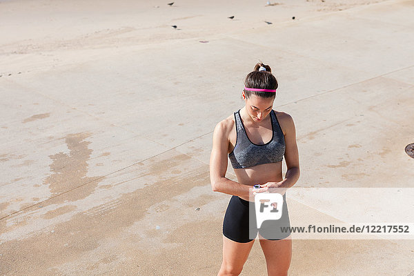 Junge Frau am Strand schaut auf Fitnesstrainer  Carcavelos  Lissabon  Portugal  Europa