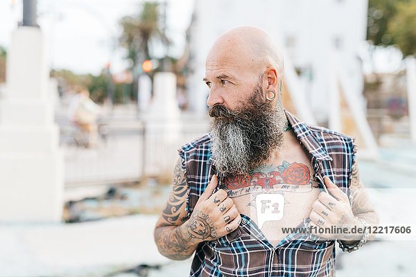 Mature male hipster revealing tattooed chest