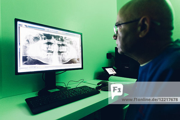 Zahnarzt sieht sich Röntgenbilder am Computer an