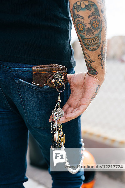 Rear view of man with keys in back pocket and skull tattoo  cropped