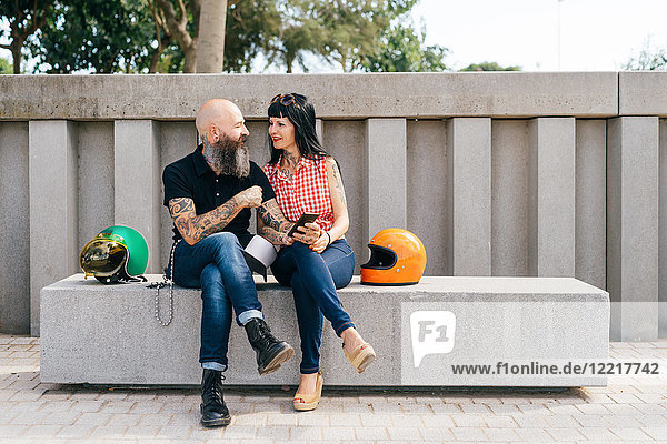 Tätowiertes reifes Hipster-Paar auf Betonbank sitzend
