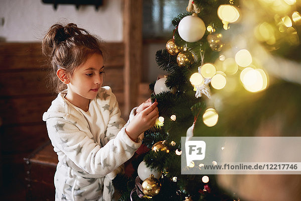 Junges Mädchen schmückt Weihnachtsbaum
