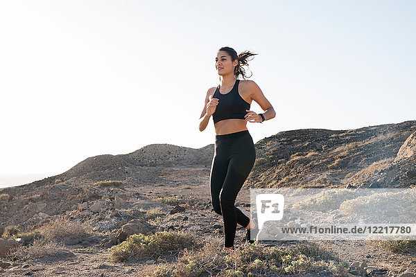 Young female runner running on dirt track in arid landscape  Las Palmas  Canary Islands  Spain
