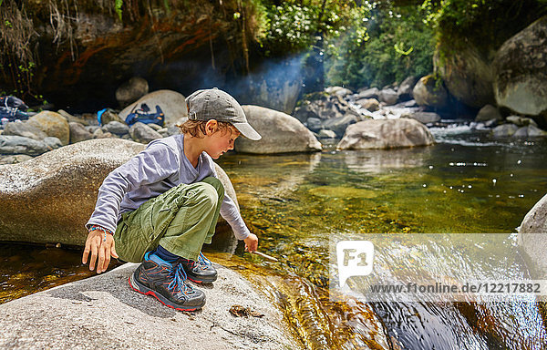 Boy crouching on rock beside water pool  Ventilla  La Paz  Bolivia  South America