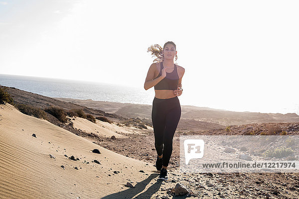 Junge Läuferin läuft in trockener Küstenlandschaft  Las Palmas  Kanarische Inseln  Spanien