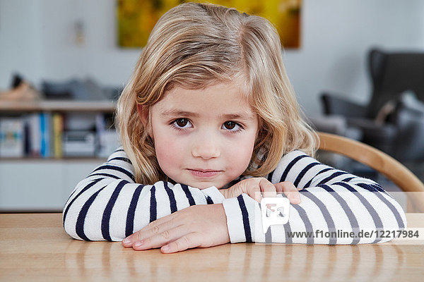 Portrait of young girl  sitting at table  pensive expression
