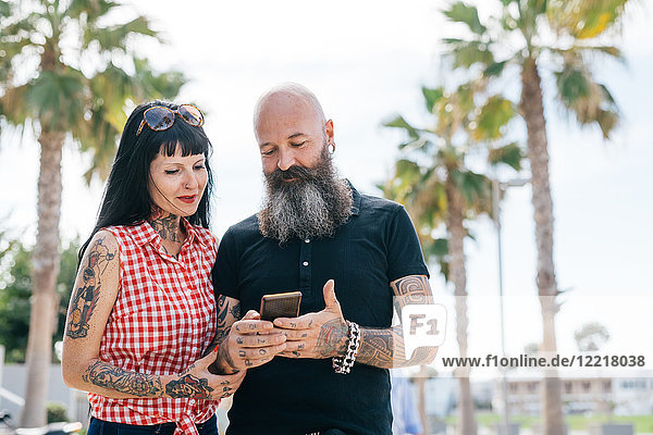 Älteres Hipster-Pärchen im Park schaut sich Smartphone an  Valencia  Spanien
