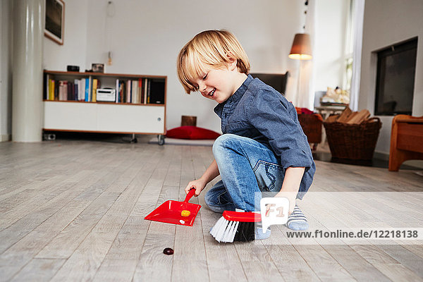 Young boy playing with toy dustpan and brush