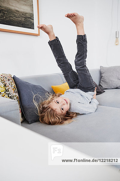 Young girl lying on sofa with legs in air