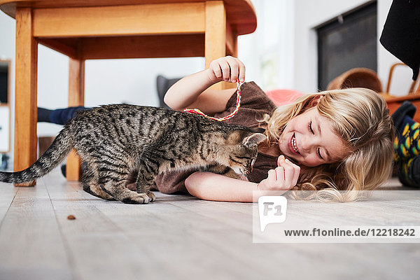 Young girl lying on floor  playing with pet cat