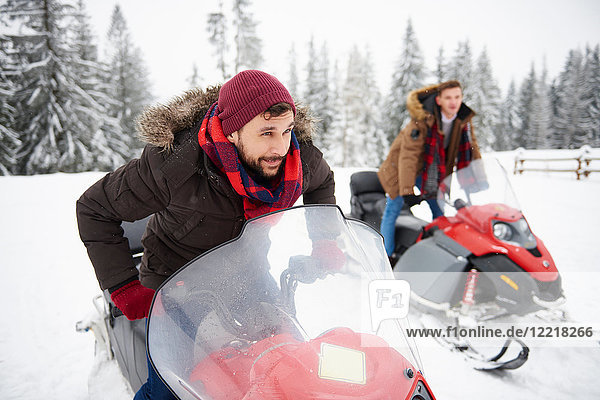 Young men riding snowmobiles in winter