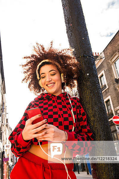 Portrait of young woman outdoors  wearing headphones  holding smartphone