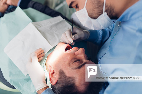 Zahnarzt schaut in den Mund eines männlichen Patienten  Ansicht von oben