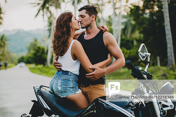 Romantic young couple embracing by motorcycle on rural road  Krabi  Thailand