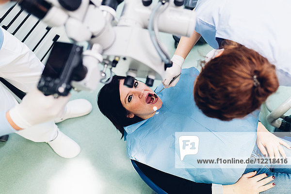 Zahnarzt  der einen Eingriff an einer Patientin durchführt  Ansicht von oben