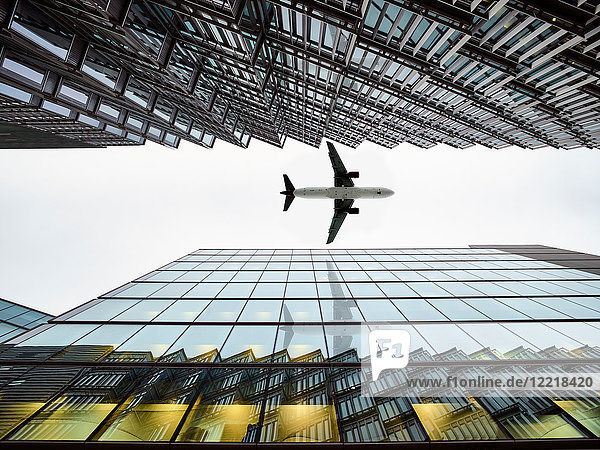 Niedrigwinkelansicht eines Flugzeugs  das zwischen modernen Gebäuden fliegt  London City Airport  London  Großbritannien