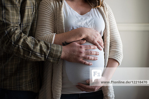 Schwangere Frau berührt Bauch  Partner zeigt Zuneigung  Mittelteil