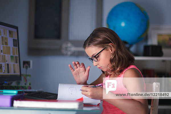 Young girl sitting at desk  doing homework  looking through book